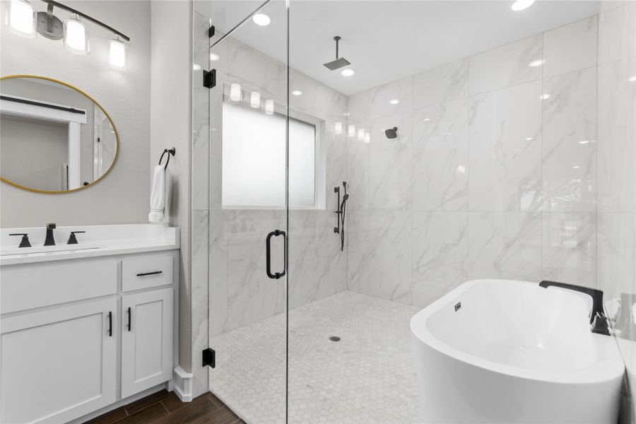 Full bathroom with a stall shower, a freestanding tub, wood finished floors, and vanity Full bathroom with a stall shower, a freestanding tub, wood finished floors, and vanity