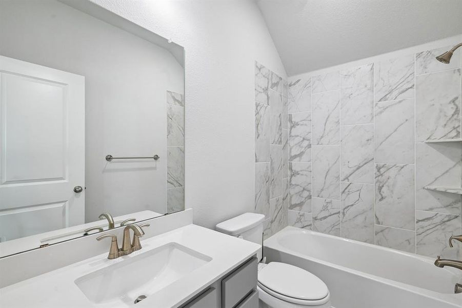 Bathroom featuring a built-in tub with a shower, patterned tile surround, and integrated shelving Bathroom featuring a built-in tub with a shower, patterned tile surround, and integrated shelving