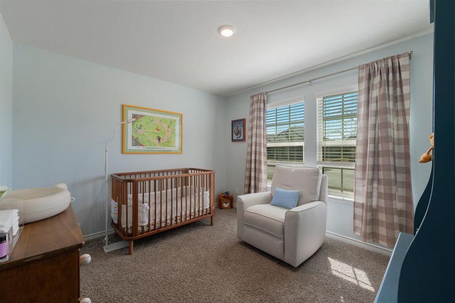 Carpeted bedroom with a crib and baseboards