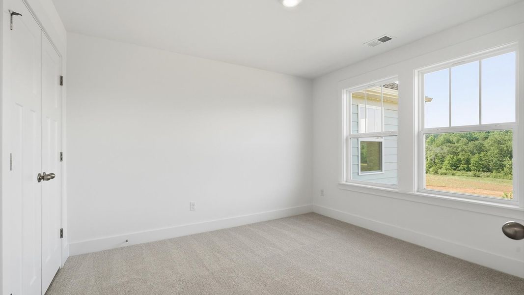 Refined bedroom design with large windows for daylight-filled mornings and peaceful views at the Pinebrook community