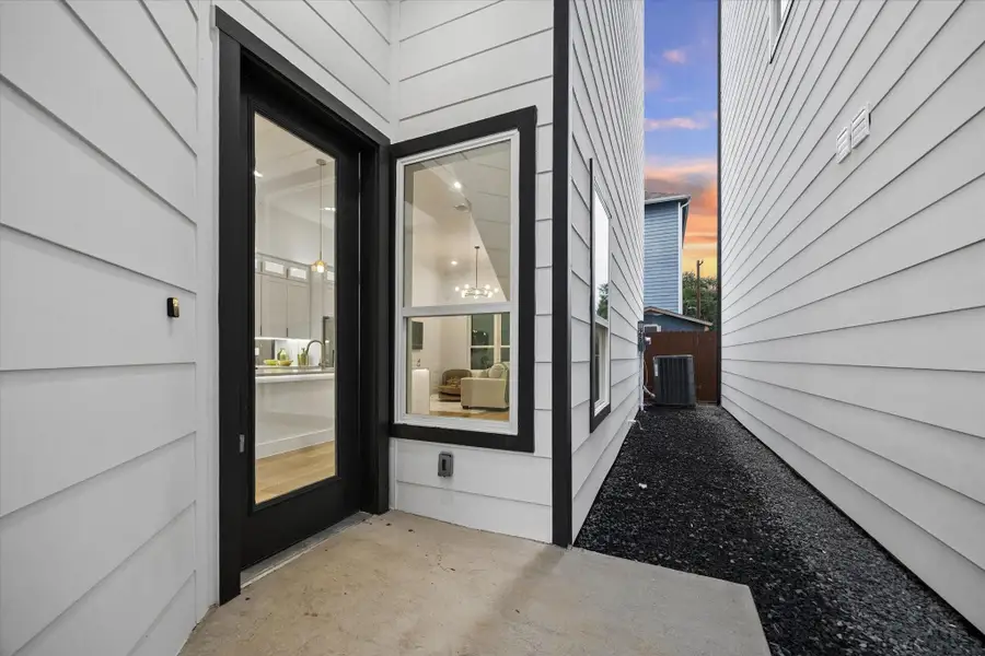 This photo shows a modern home's side entrance with large windows and a glass door, offering a glimpse into a bright, stylish interior. The exterior features crisp white siding and a narrow walkway with a gravel path leading to the backyard, all against a backdrop of a colorful sky. This photo shows a modern home's side entrance with large windows and a glass door, offering a glimpse into a bright, stylish interior. The exterior features crisp white siding and a narrow walkway with a gravel path leading to the backyard, all against a backdrop of a colorful sky.