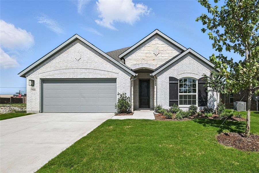 French country inspired facade featuring an attached garage, a front yard, driveway, and brick siding French country inspired facade featuring an attached garage, a front yard, driveway, and brick siding