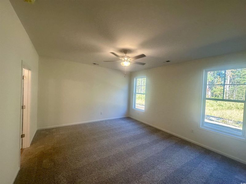 Master bedroom featuring dark colored carpet, ceiling fan, and a textured ceiling