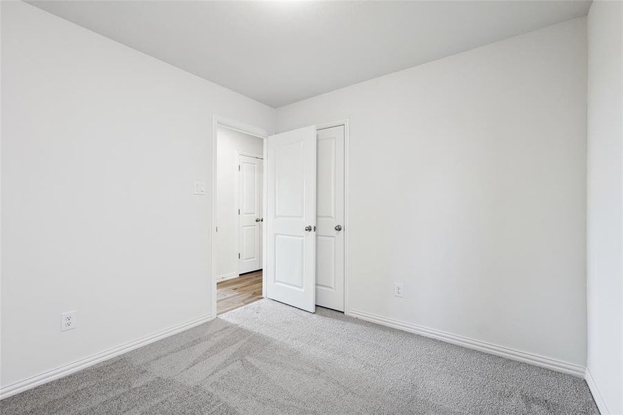 Unfurnished bedroom with light colored carpet and baseboards