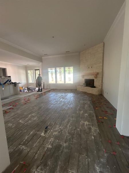 Unfurnished living room with dark wood-style floors, crown molding, and a large fireplace