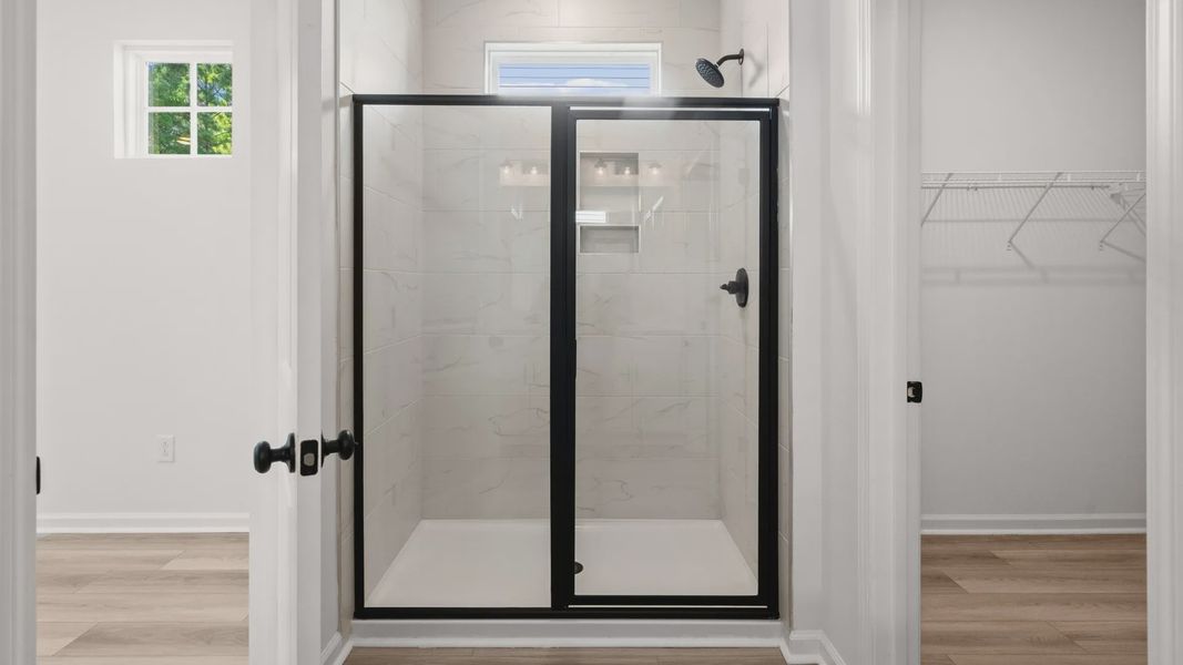 Step into a tiled walk-in shower framed by sleek glass doors