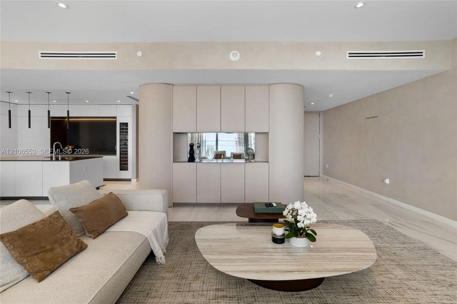 Custom floor-to-ceiling cabinetry with curved end-caps, integrated mirror-back shelving, recessed lighting, and stone-finish flooring