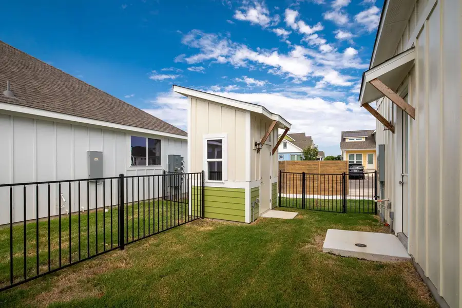 Gently sloping green grass fills a fenced side yard featuring a matching detached shed. Gently sloping green grass fills a fenced side yard featuring a matching detached shed.