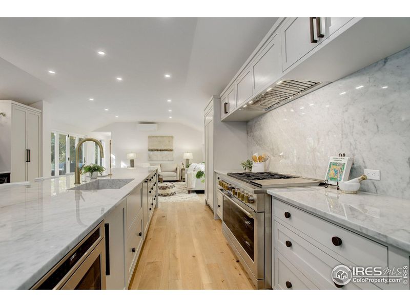 The heart of this home, the chef's kitchen, features an 17ft White Carrara Marble island with waterfall edges and top-of-the-line Monogram appliances.