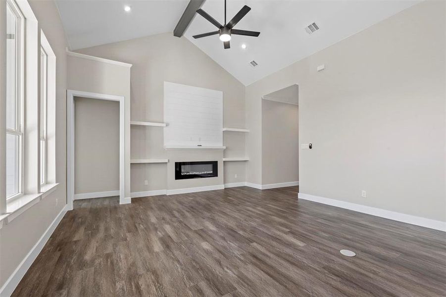 Unfurnished living room featuring high vaulted ceiling, ceiling fan, beamed ceiling, and dark hardwood / wood-style floors