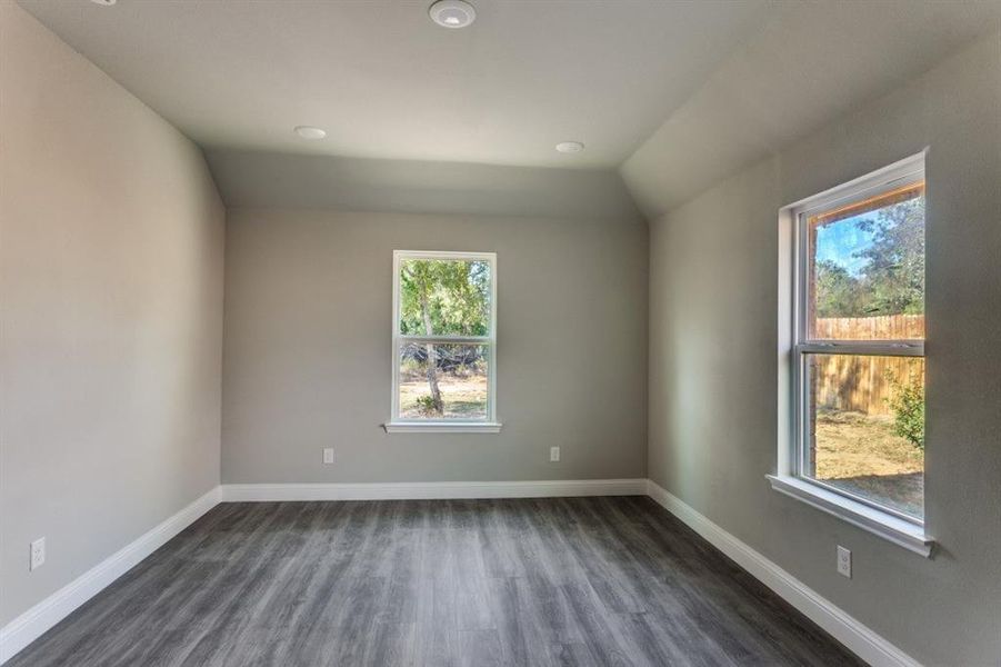 Empty room with dark wood finished floors, recessed lighting, and lofted ceiling