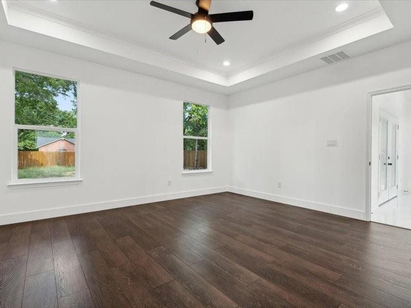 Unfurnished room featuring dark hardwood / wood-style flooring, ceiling fan, a raised ceiling, and ornamental molding