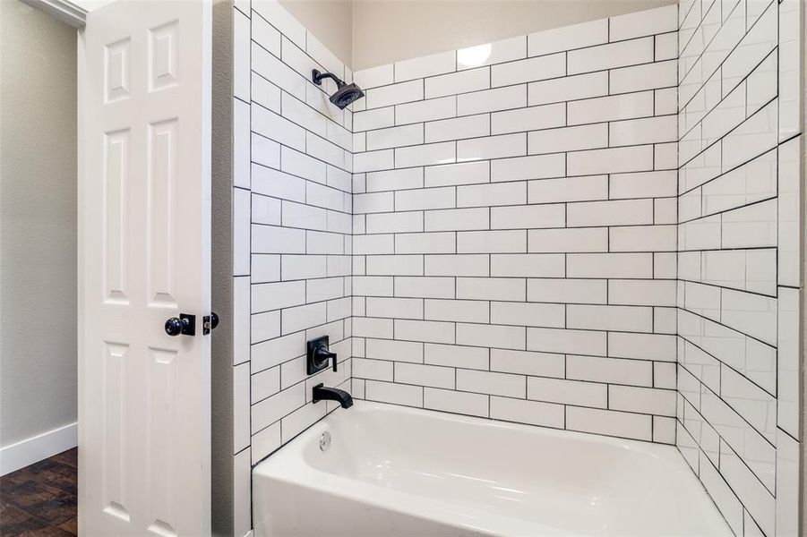 Bathroom featuring hardwood / wood-style flooring and tiled shower / bath combo