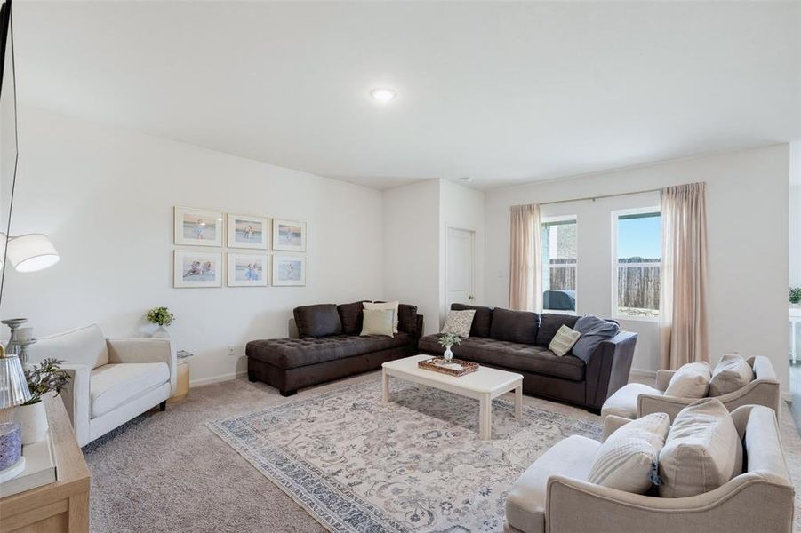 Carpeted living area featuring recessed ceiling lighting, a white painted door, and two windows with light-colored drapes