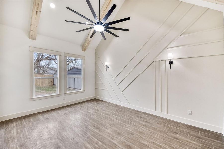Bonus room with light wood-type flooring, vaulted ceiling with beams, a decorative wall, and ceiling fan