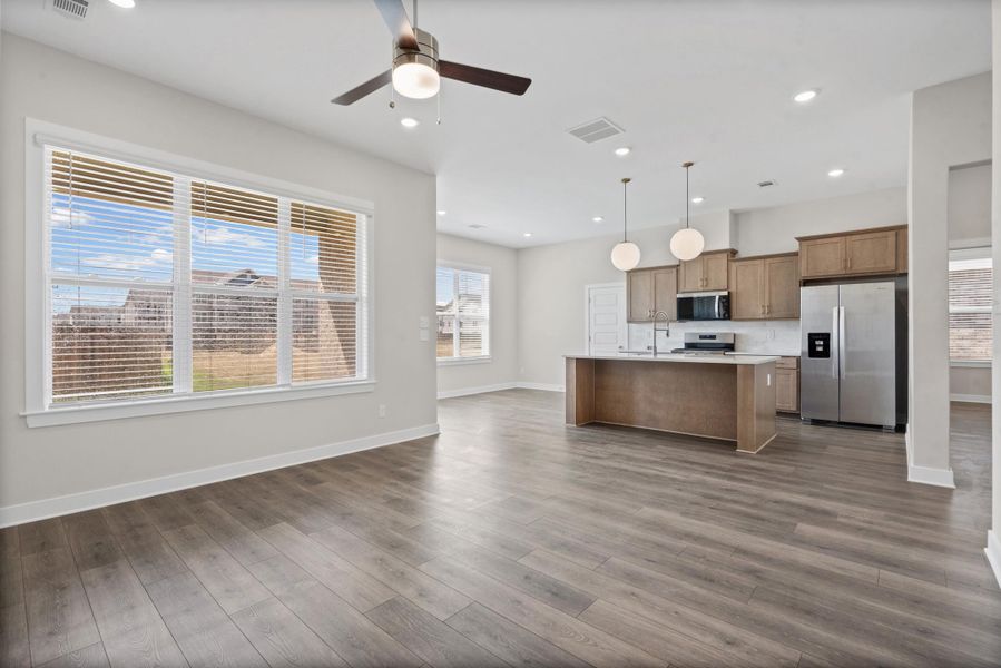 Spacious living area featuring wood-finish flooring, a ceiling fan, and large windows