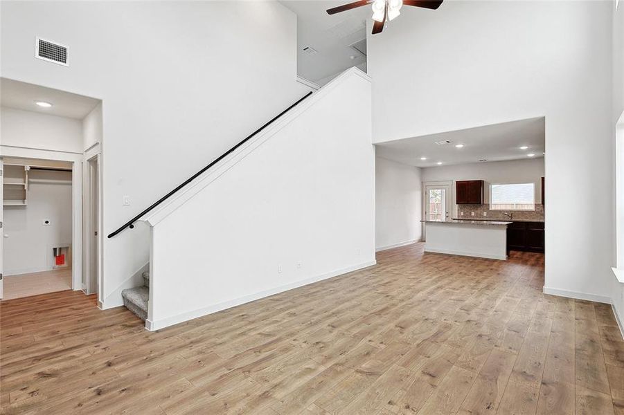 Unfurnished living room featuring a high ceiling, light hardwood / wood-style floors, and ceiling fan