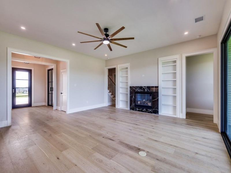 Unfurnished living room with ceiling fan, baseboards, built in shelves, light wood-style floors, and recessed lighting