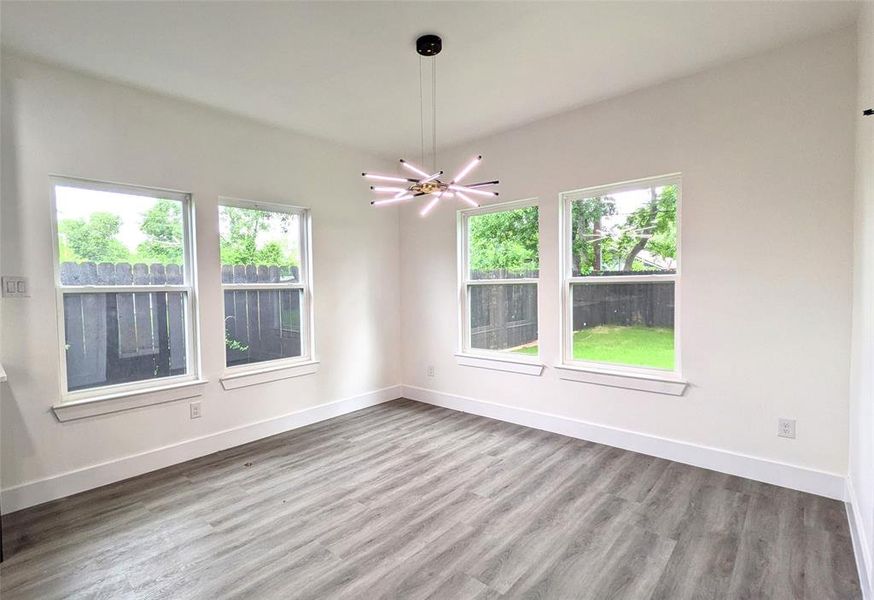 Empty room with baseboards, a notable chandelier, and wood finished floors