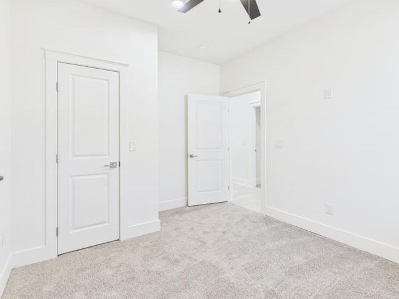 Unfurnished bedroom with light carpet and ceiling fan Unfurnished bedroom with light carpet and ceiling fan