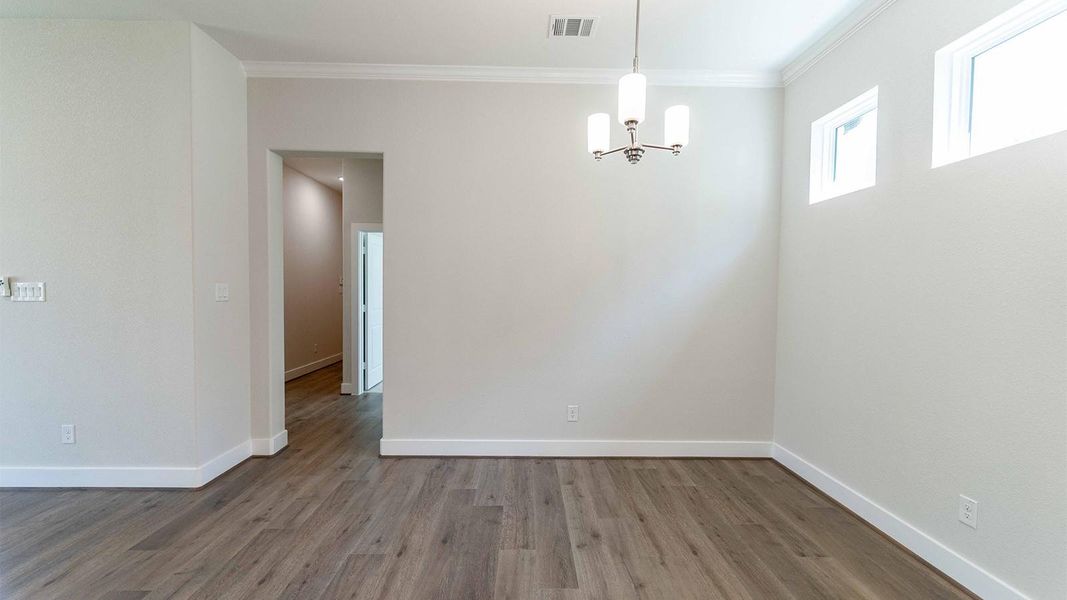 Unfurnished dining area featuring ornamental molding, wood finished floors, and a chandelier Unfurnished dining area featuring ornamental molding, wood finished floors, and a chandelier