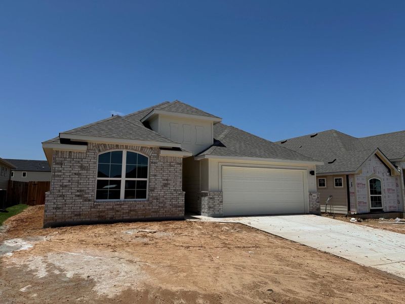 French country style house featuring an attached garage, brick siding, a shingled roof, and driveway French country style house featuring an attached garage, brick siding, a shingled roof, and driveway