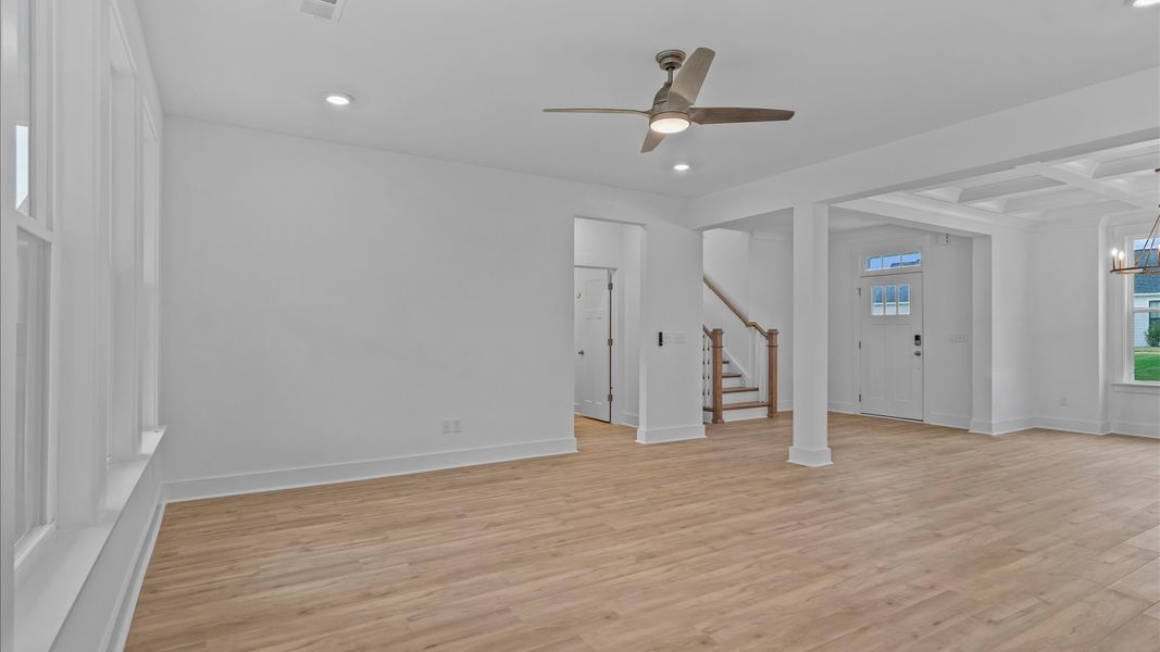 Elegant family room featuring hardwood flooring, large windows, and ceiling fan