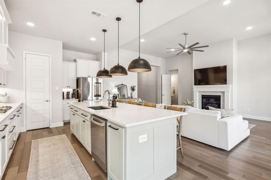 Kitchen with pendant lighting, an island with sink, sink, white cabinetry, and appliances with stainless steel finishes