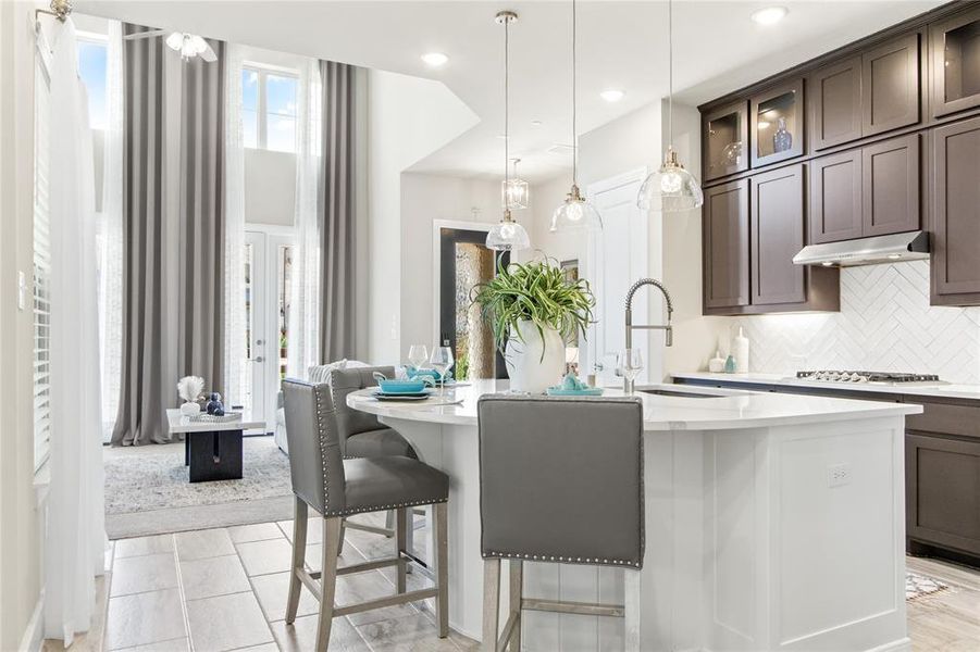 Kitchen with an island with sink, tasteful backsplash, dark brown cabinets, and pendant lighting