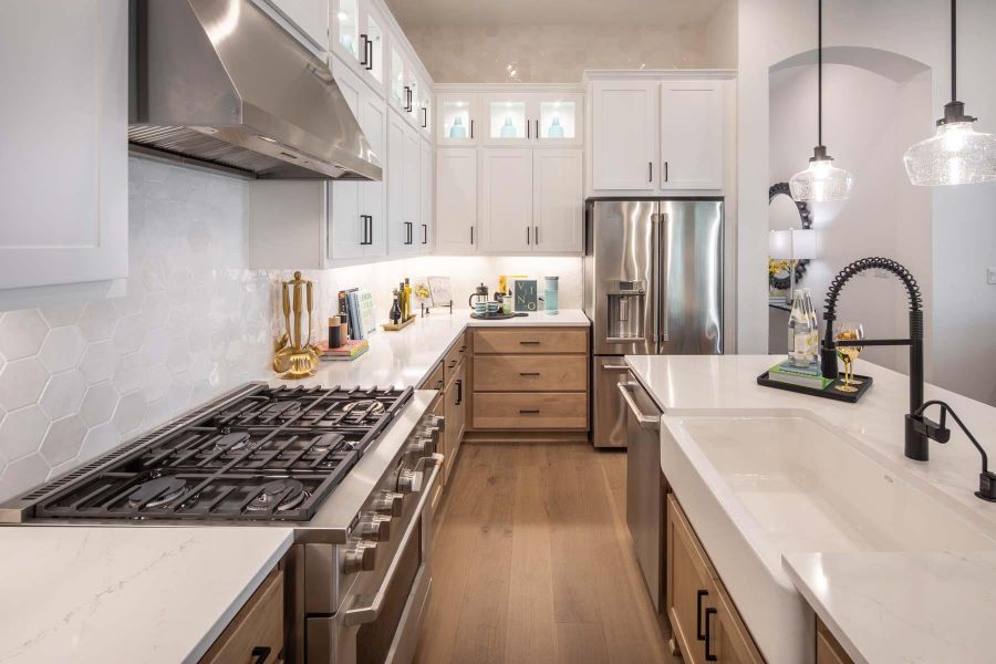 Kitchen featuring decorative light fixtures, range hood, wood finished floors, stainless steel appliances, and a sink