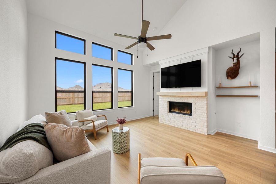 The living room has plenty of large windows and a bricked electric fireplace.