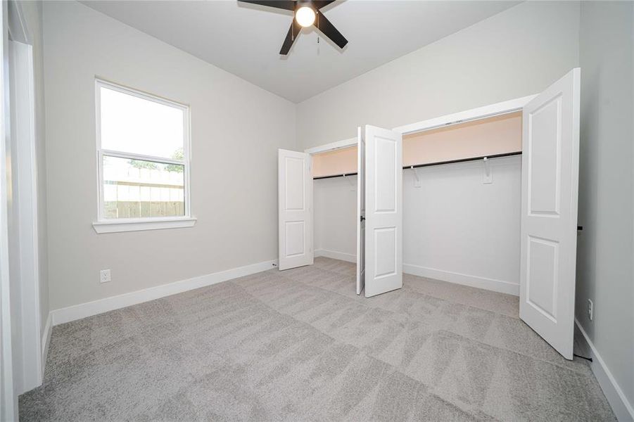 Unfurnished bedroom with light carpet, a ceiling fan, and a closet Unfurnished bedroom with light carpet, a ceiling fan, and a closet