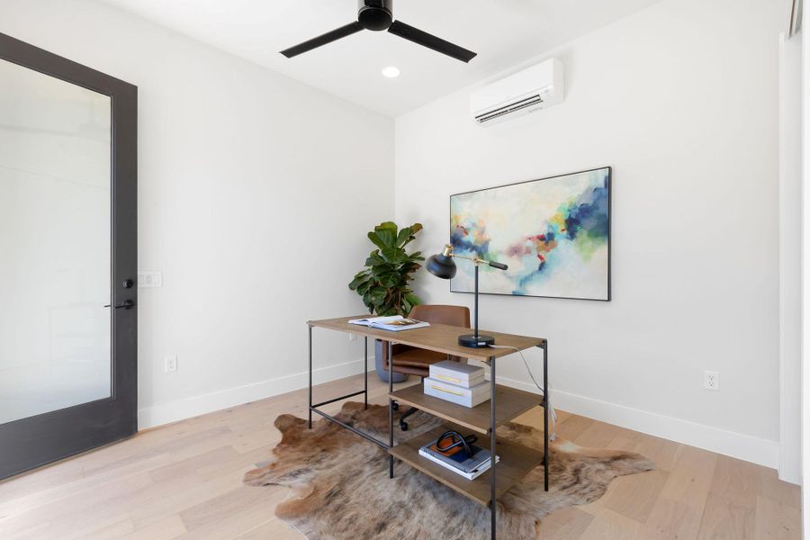 Office area with wood finished floors, baseboards, and a wall mounted AC