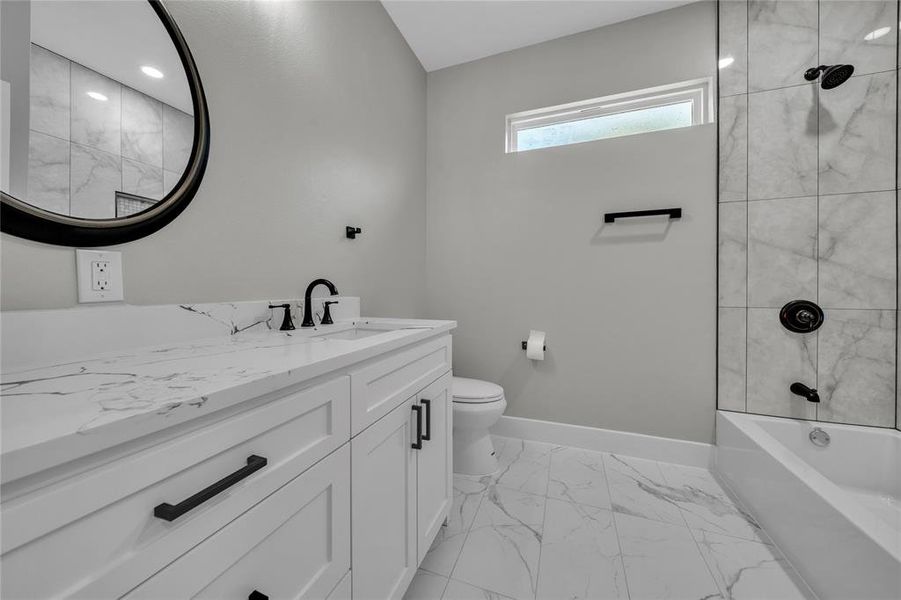 Full bathroom featuring vanity, tiled shower / bath combo, toilet, and tile patterned flooring