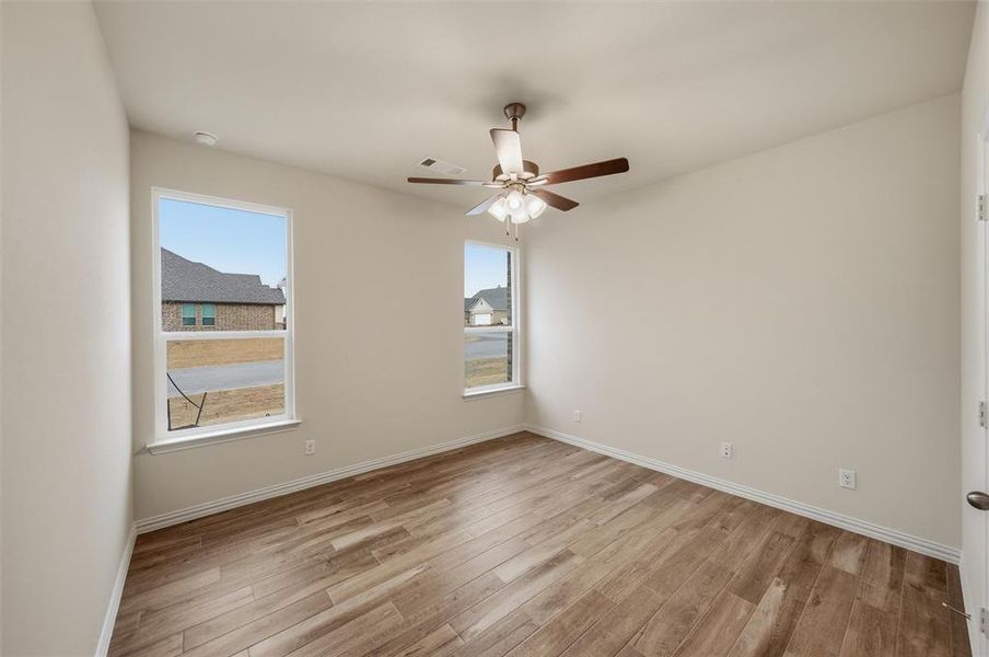 Spare room featuring light wood-style floors, healthy amount of natural light, and a ceiling fan