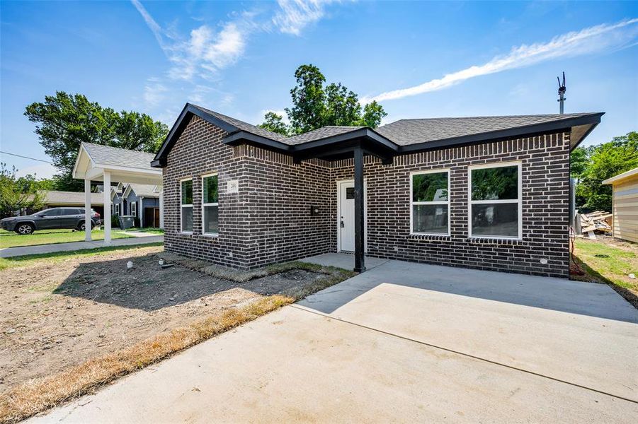 View of front of home with brick siding and roof with shingles