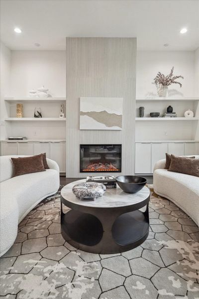 Striking modern fireplace framed by vertical textured detailing and symmetrical built-in shelving. Clean lines and a neutral palette create a refined focal point within the living area. The balanced architectural composition enhances the room’s sophistication while maintaining warmth and visual interest, blending contemporary design with timeless appeal.