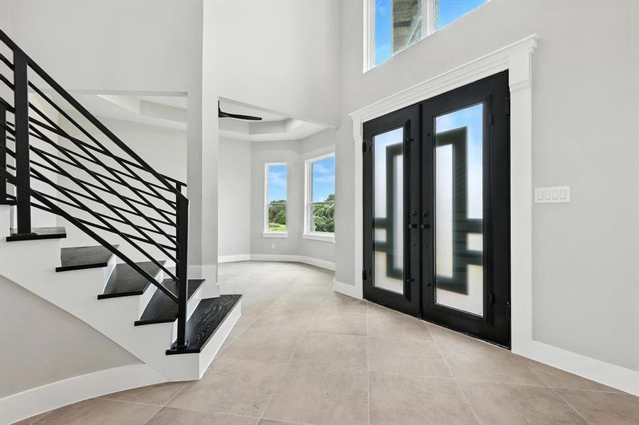 Tiled foyer featuring stairway and french doors