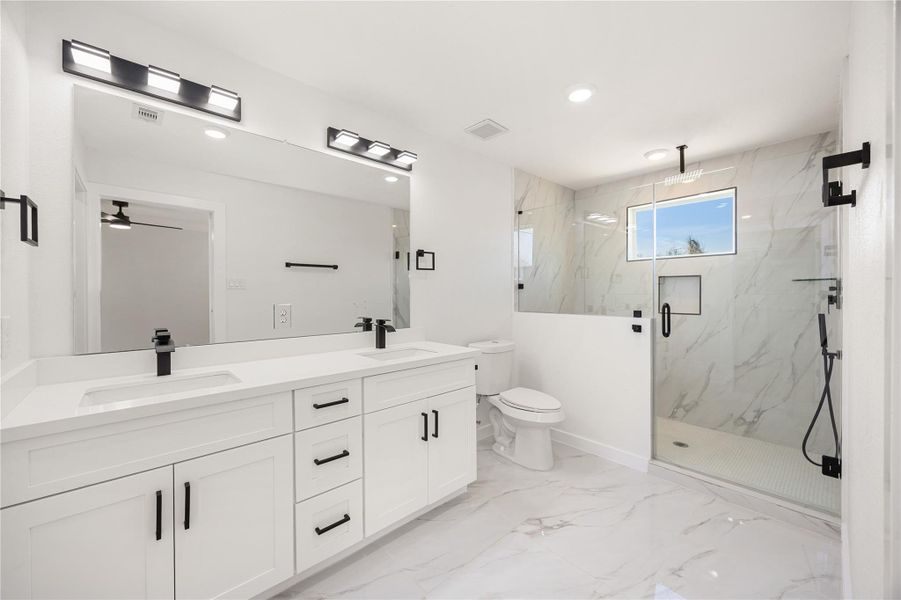 Spa-inspired primary bathroom featuring a dual-sink vanity, quartz countertops, sleek black fixtures, and a walk-in glass shower with modern tile surround. Spa-inspired primary bathroom featuring a dual-sink vanity, quartz countertops, sleek black fixtures, and a walk-in glass shower with modern tile surround.