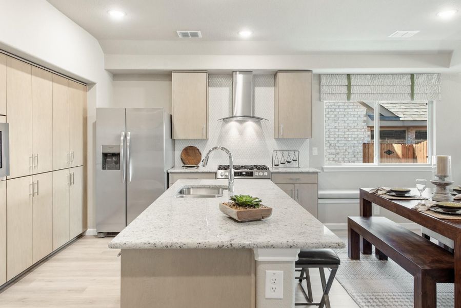 Kitchen with granite island, stainless steel appliances, light wood cabinets, and adjacent dining area with bench seating Kitchen with granite island, stainless steel appliances, light wood cabinets, and adjacent dining area with bench seating
