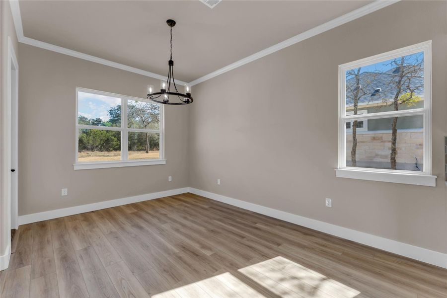 Unfurnished room featuring light wood finished floors, ornamental molding, and a chandelier
