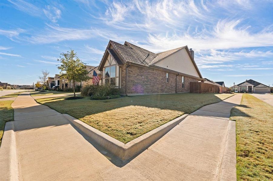 View of property exterior featuring brick siding, a lawn, a chimney, and a residential view
