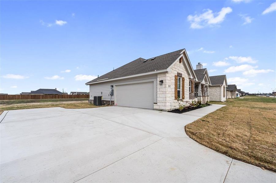View of property exterior with stone siding, a shingled roof, a chimney, driveway, and a garage View of property exterior with stone siding, a shingled roof, a chimney, driveway, and a garage