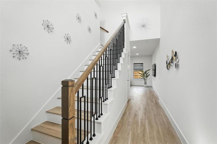 Stairs featuring wood finished floors, recessed lighting, and a towering ceiling