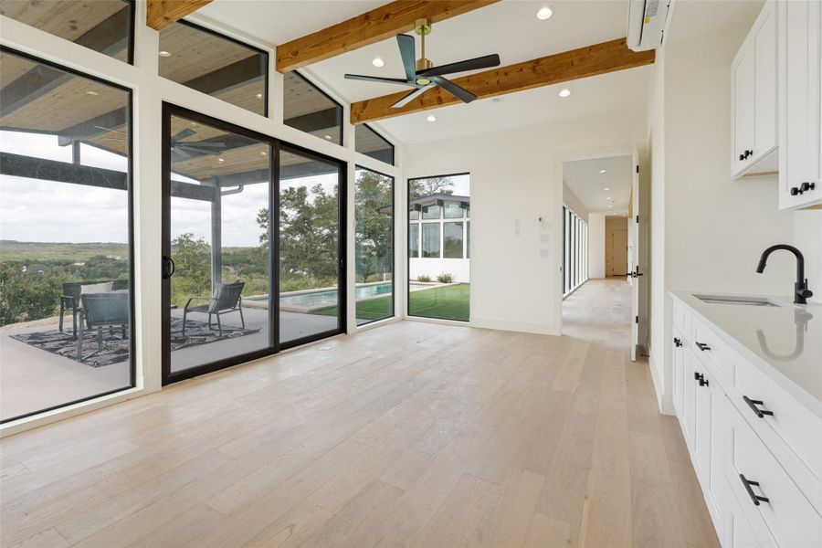 Exposed wood beams adorn the ceiling of this serene bedroom, offering panoramic nature views through expansive windows.