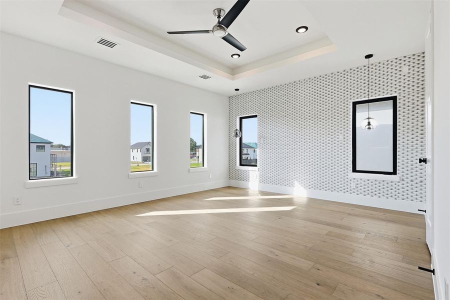The Primary Bedroom includes a recessed tray ceiling, wide-plank wood flooring, and a patterned accent wall with dual pendant lights.