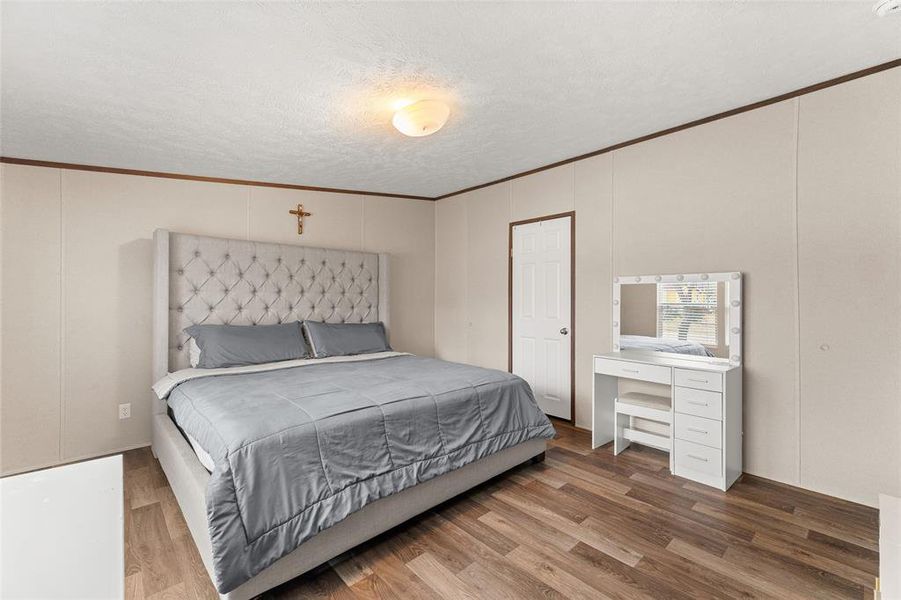 Bedroom with wood finished floors, ornamental molding, and a textured ceiling