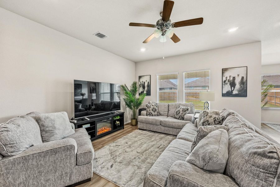 Natural light floods this inviting living space, complete with durable wood flooring and a cozy fireplace.