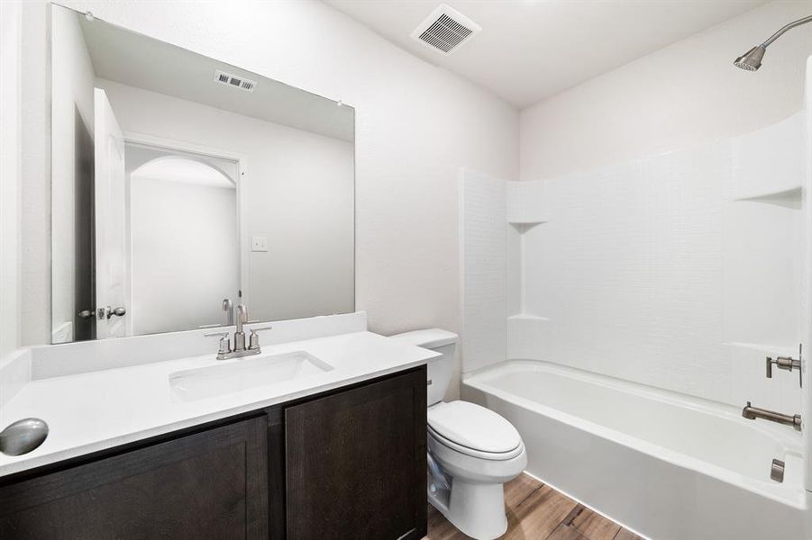 Full bathroom with shower / tub combination, hardwood / wood-style floors, toilet, and vanity