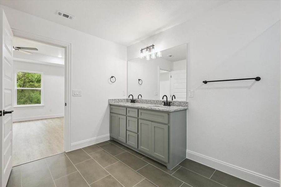 Bathroom with double vanity, dark tile patterned flooring, and a ceiling fan Bathroom with double vanity, dark tile patterned flooring, and a ceiling fan